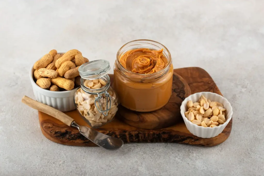 Jar of almond butter and peanut butter placed side by side with nuts and nutritional comparison elements on a kitchen surface.