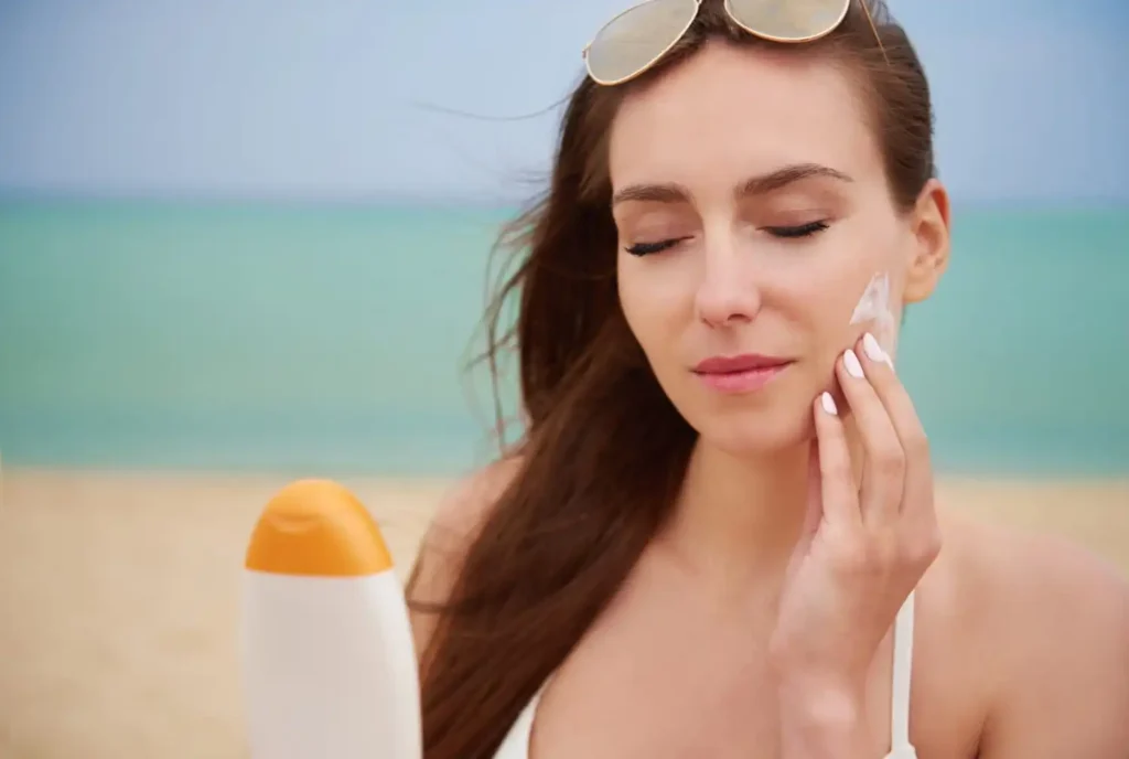 Person applying mineral sunscreen to the face while reviewing sunscreen ingredients and sun protection information.