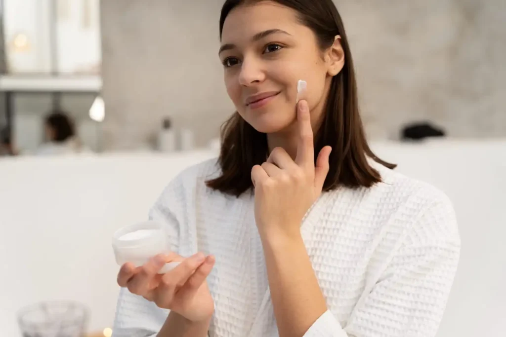 Person applying CeraVe moisturizing lotion to the face as part of a skincare routine for hydration and acne-prone skin care.