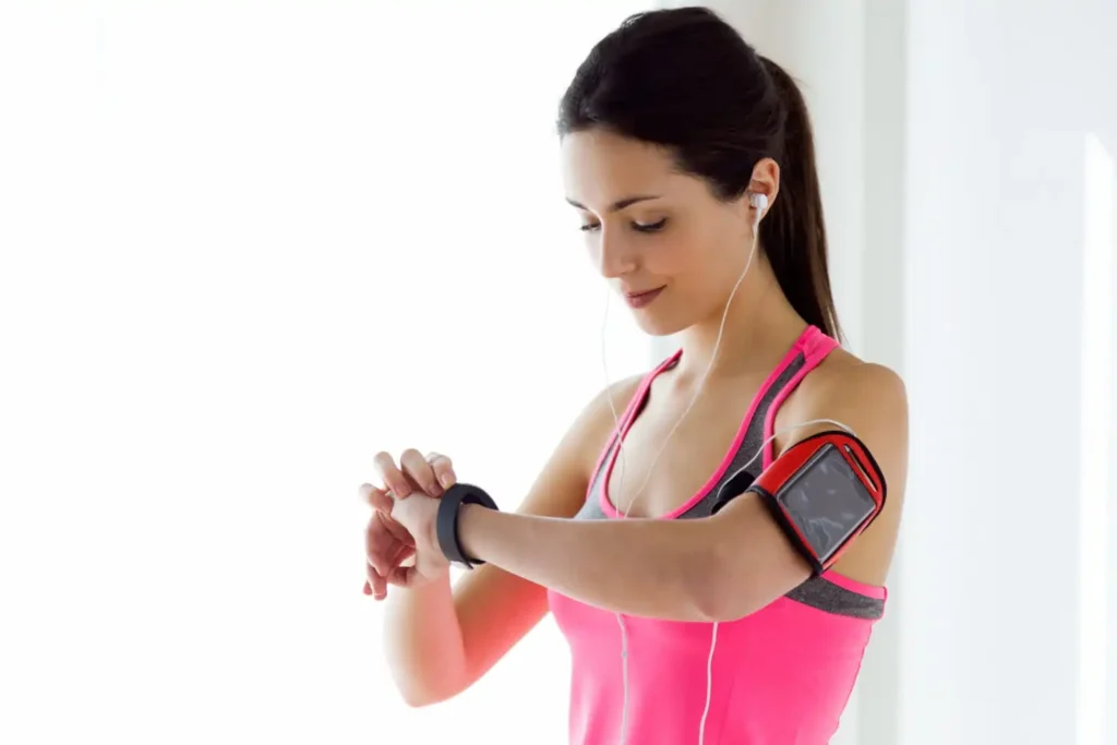 Person checking health metrics on a fitness smartwatch while walking outdoors, with a smartphone displaying activity and wellness data.