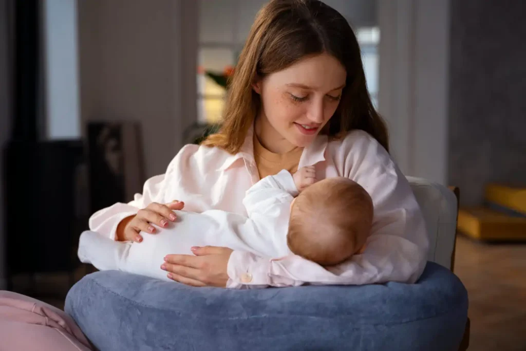 Parent holding a newborn in a comfortable breastfeeding position while receiving guidance on proper latch, support, and infant feeding.